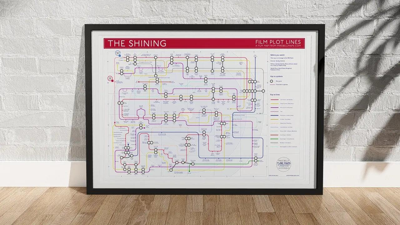 The Shining plot map film wall art print with red header in a black A1 landscape frame, hung on a feature wall, showing the full 1980 Kubrick film as a tube map of characters and plot points, designed by Mike Bell at mikebellmaps.com.