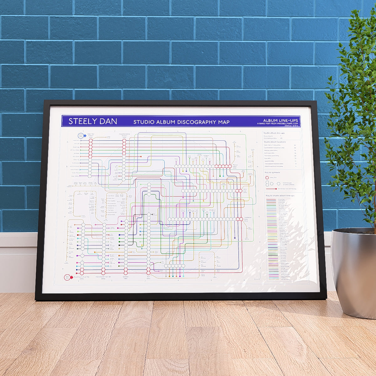 Steely Dan discography tube map in A1 (594x841mm, 24x36in), framed Giclée wall art print propped against a wall on the floor, designed by Mike Bell.