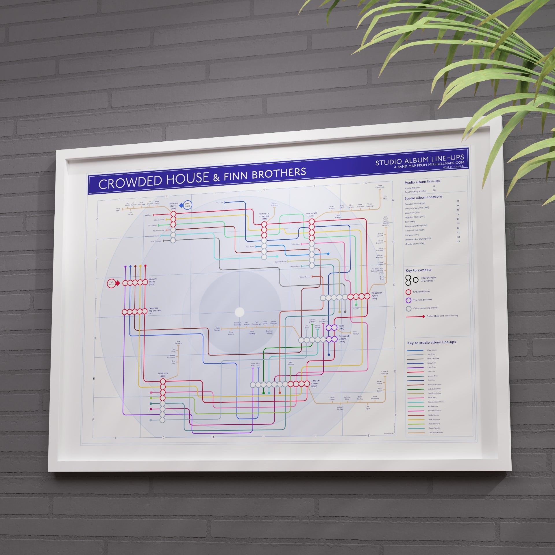 Framed Crowded House diagram on a gray brick wall with a plant to the right