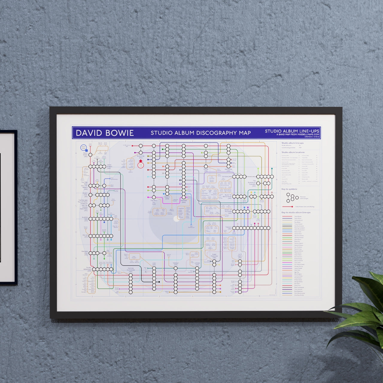 David Bowie discography tube map in A2 size, framed Giclée wall art print hung on a wall, ideal gift for Bowie fans - the same map is held in the permanent collection at the V&A David Bowie Centre, V&A East Storehouse, London, designed by Mike Bell.