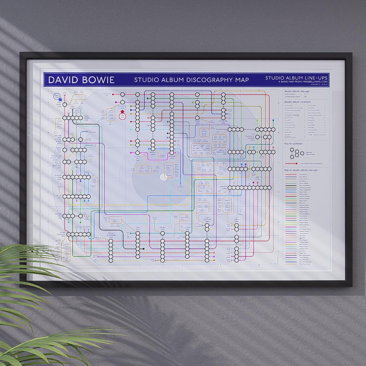 David Bowie discography map displayed in a styled lounge setting, A1 landscape black framed wall art print against a white brick wall, from Mike Bell&