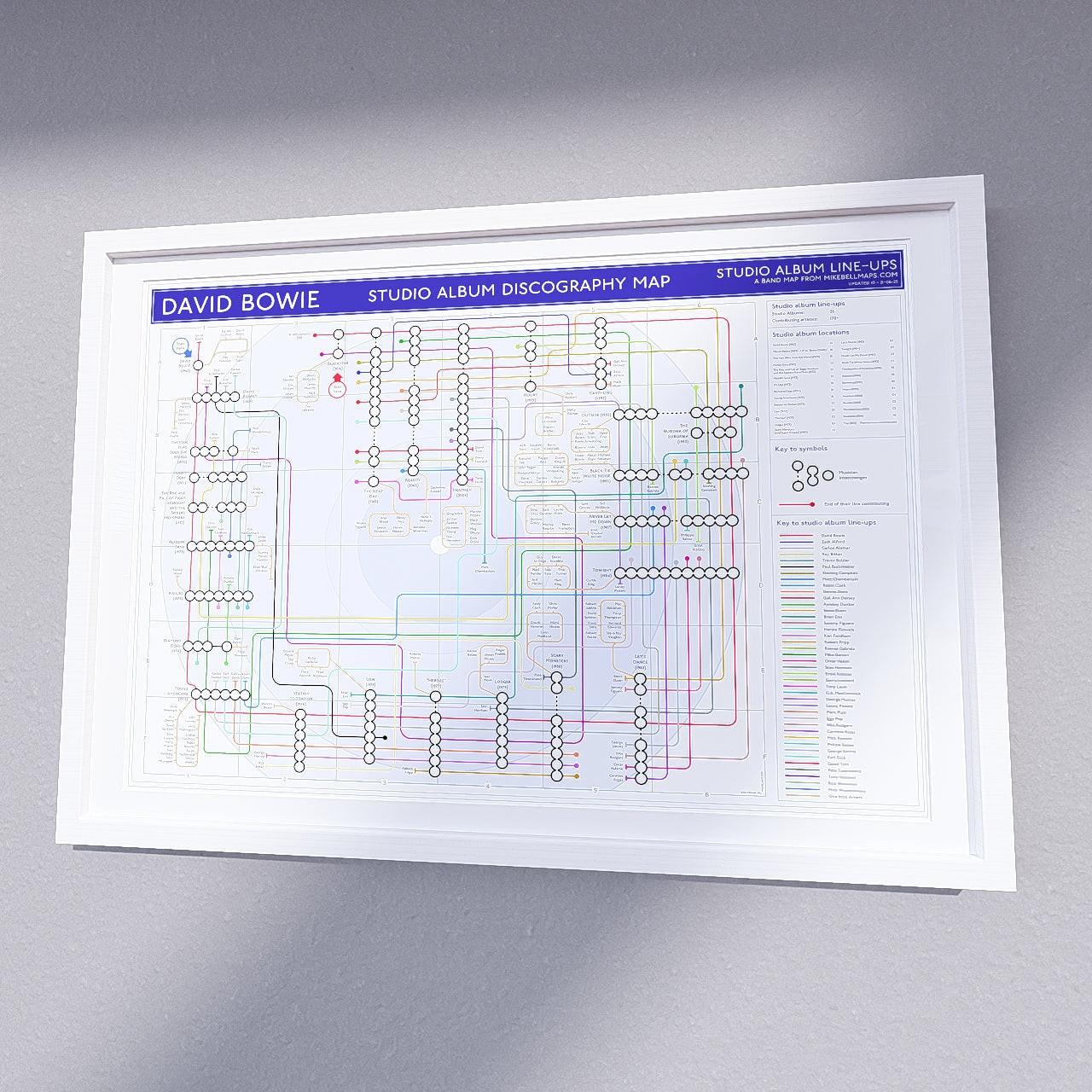 David Bowie music map in a white A2 landscape frame, styled on a contemporary dark wood slatted office wall above a desk, premium wall art print from mikebellmaps.com.