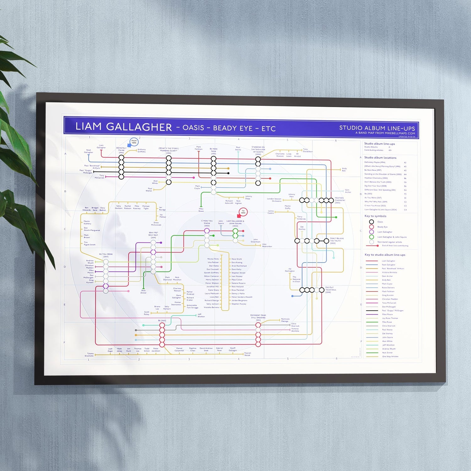 Liam Gallagher discography tube map hung in an A1 black wooden frame on a plain wall, landscape Giclée wall art print, designed by Mike Bell.