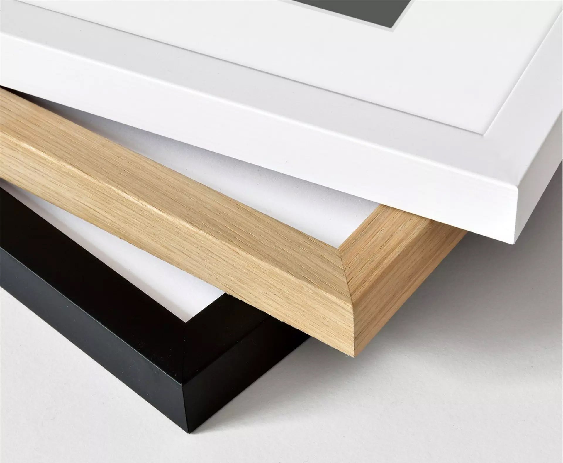 Picture frames in white, black, and wood on a light gray surface for Mike Bell maps art prints