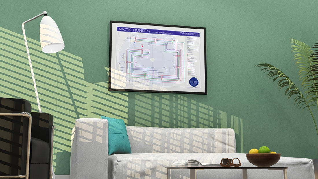 Living room with a white sofa, black armchair, floor lamp, and Arctic Monkeys discography map poster on a gray wall.