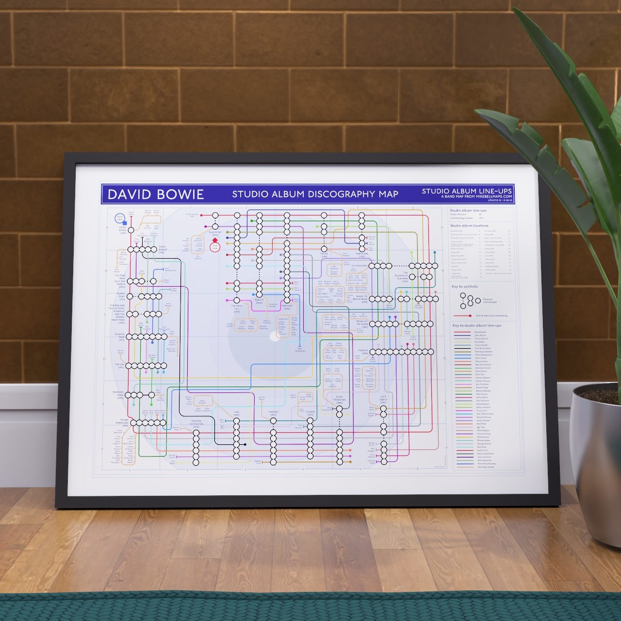 David Bowie discography tube map in A1 size, framed Giclée wall art print propped against a wall on the floor, framed art print gift for Bowie and Ziggy Stardust fans, designed by Mike Bell.