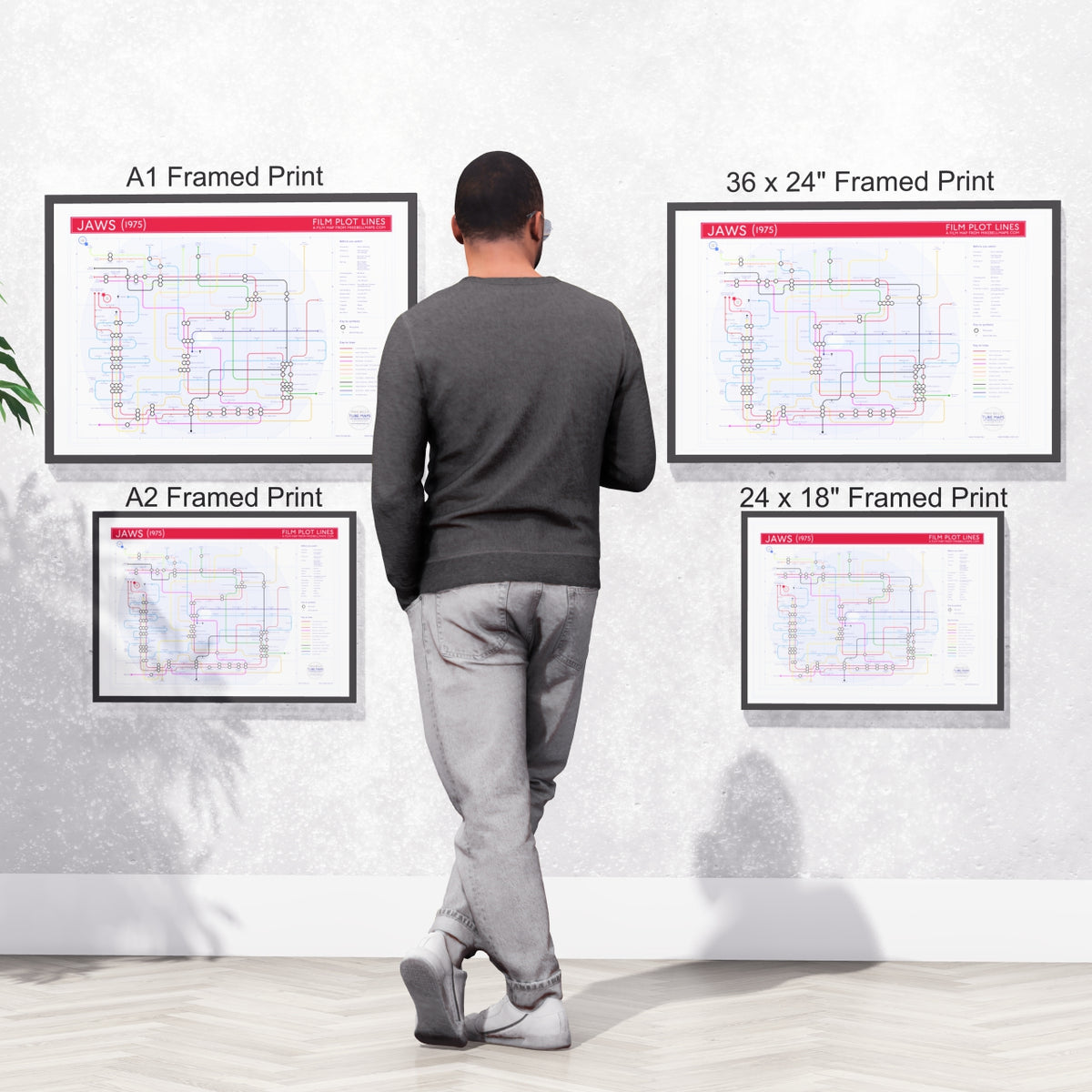 A viewer studying four framed Jaws plot map wall art prints in different sizes displayed on a wall, designed by Mike Bell.