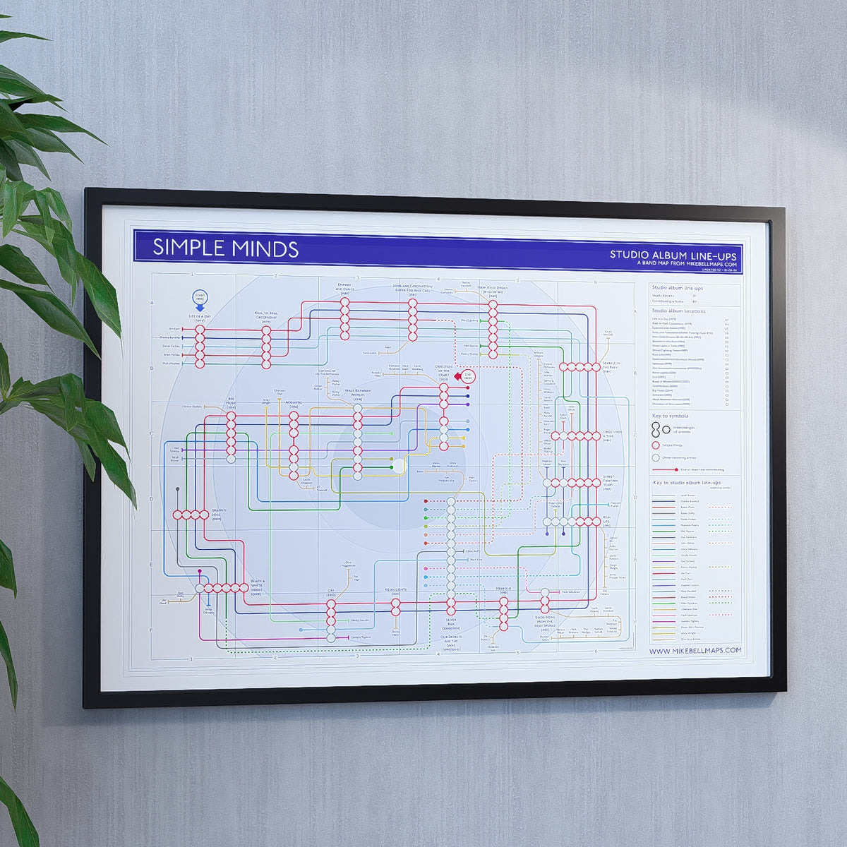 Simple Minds discography map art print in A1 (841 x 594 mm), framed in black wood and hung on a wall, designed by Mike Bell.